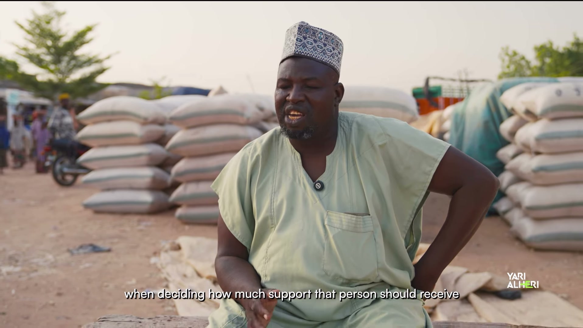 A market representative speaks among sacks of farm produce in Talata Mafara. Film still.
